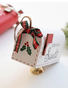 Detail of white wooden Santa letter mailbox ornament with plaid bow and golden bell