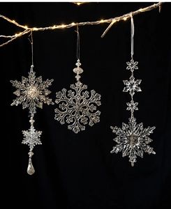 Three-piece set of transparent acrylic snowflakes hanging on a festive warm lighted branch