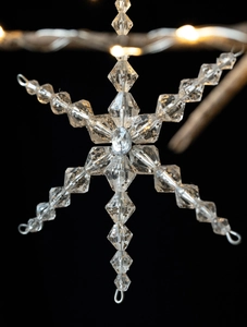 Close-up of clear acrylic snowflake pendant with gold glitter beads and metal wire