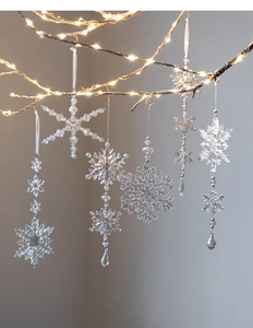 Macro detail of acrylic snowflake ornaments hanging on branches with warm LED festive lights