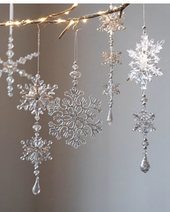 Macro detail of acrylic snowflake ornaments hanging on branches with warm festive lighting