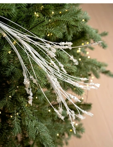 Detailansicht verschneiter weißer Weihnachtsbaumzweige mit klaren Eis-Kristall-Perlen