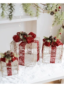 Dettaglio di scatole regalo di Natale in filo metallico con nastri rossi e pigne