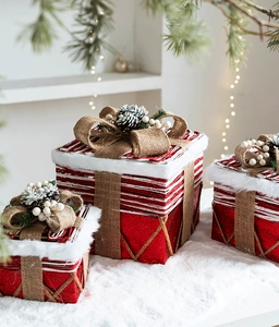 Dettaglio di scatole regalo di Natale rosse glitterate con fiocchi di iuta e pigne innevate