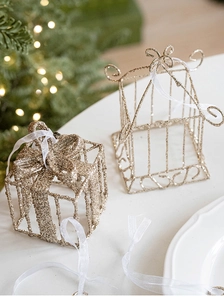 Détail de décorations de Noël dorées en fer avec paillettes et rubans en soie blanche
