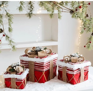 Dettaglio di scatole regalo di Natale rosse e bianche con pigne e fiocchi su neve finta