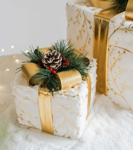 Dettaglio di scatole regalo di Natale in peluche bianco con nastri dorati e pigne decorative