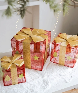 Set di tre scatole regalo di Natale rosse con fiocchi dorati su sfondo di neve bianca