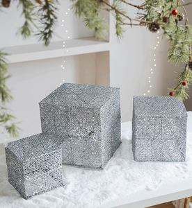 Dettaglio di tre scatole regalo natalizie in argento con rete glitterata su neve
