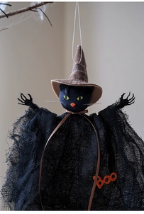 Detail of Halloween black cat doll in mesh robe with Boo sign and wizard hat hanging