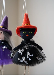 Detail of black cat wizard ornament with orange hat and silver skull print mesh skirt