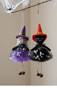 Detail of Halloween witch and black cat ornaments with tulle skirts and bells hanging on branch