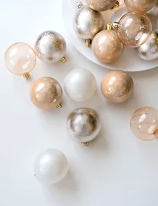 Detail view of 6cm champagne gold and silver Christmas balls with various textures on a white tray