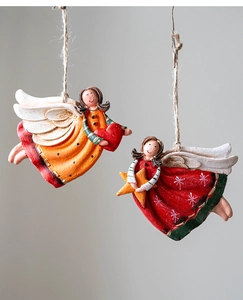 Detail of two resin Christmas angel ornaments with red heart and golden star accents