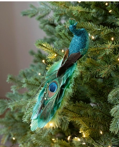 Detailed view of blue peacock bird ornament with feathers on a glowing Christmas tree