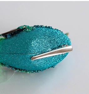 Detail of the metal alligator clip on the back of the teal glitter Christmas ornament