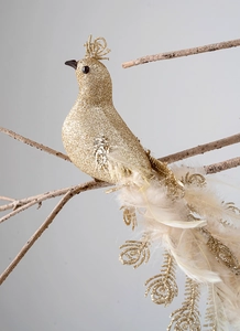 Close-up of champagne gold glitter bird ornament with feather tail on tree branch decoration