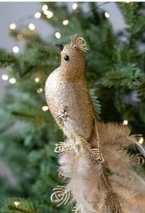 Macro shot of a golden glitter bird ornament with real feathers on a Christmas tree branch