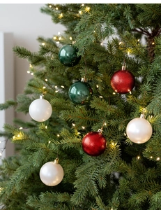 Close-up of red, green and white Christmas ball ornaments hanging on a lighted tree