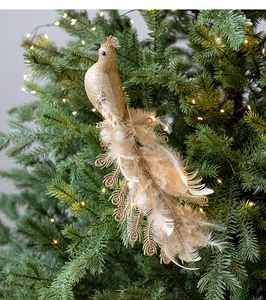 Close-up of golden bird Christmas ornament with feathers and glitter on green pine branches