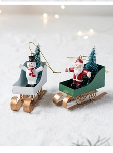 Close-up of Santa and Snowman sleigh ornaments with golden metal frames and trees
