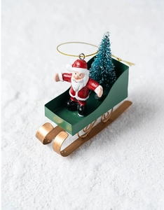 Detail of Santa Claus on a green sleigh with a snowy tree and golden hangers
