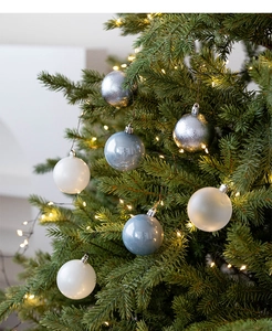 Close-up of matte and glossy Christmas balls in white, blue, and silver on tree