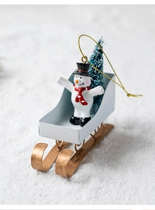 Detail of Christmas snowman on white iron sled with golden rails and mini pine tree