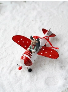 Detail of a red iron plane ornament with reindeer pilot on snowy background