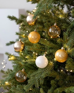 Close-up of 6cm Christmas balls with matte and glossy finishes hanging on a lighted tree
