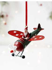 Detail of vintage metal Santa Claus pilot ornament with red wings on a Christmas tree