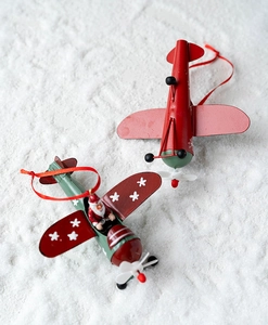 Detail of vintage metal Christmas plane ornaments with Santa pilot on white snowy background