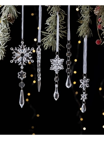 Detail of clear acrylic Christmas icicles and snowflake ornaments hanging on pine branches