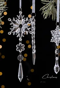 Close-up of transparent snowflake and icicle ornaments with white ribbons on pine branch