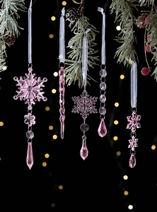Pink crystal snowflakes and icicle ornaments hanging on a snowy Christmas tree branch