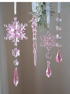 Detailed view of pink acrylic Christmas snowflake ornaments on a green pine branch