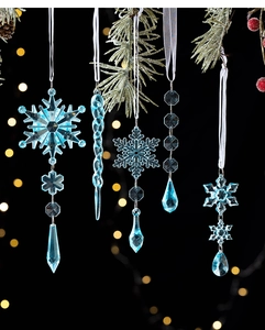Close-up of clear blue snowflake and icicle ornaments hanging on frosty pine branches