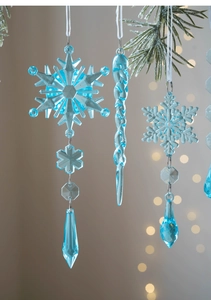 Detail of blue transparent acrylic snowflake and icicle ornaments hanging on Christmas branches