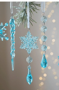 Macro detail of transparent snowflake and icicle ornaments hanging on green pine branches
