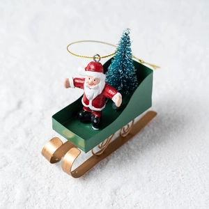 Metal Santa Claus on green sleigh with mini Christmas tree, festive holiday hanging decor