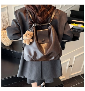 Detail of dark brown leather cloud backpack with a cute plush bear charm on side