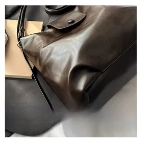 Close-up of a dark brown leather cloud bag with premium texture and flap button detail