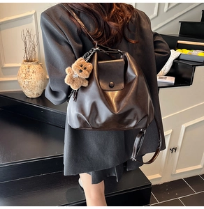 Brown PU leather bucket bag with flap closure and cute bear pendant on a grey suit model