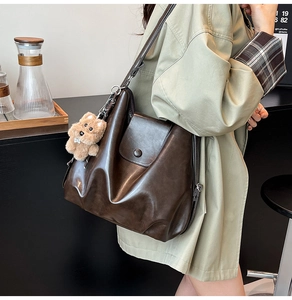Detail of vintage dark brown faux leather bag with a cute plush dog charm attached