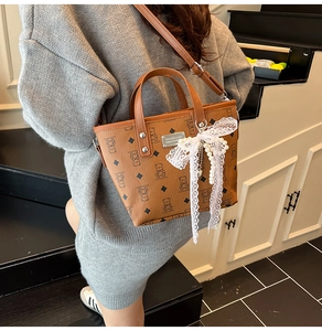 Détail du sac cabas en similicuir marron avec ours imprimé, nœud dentelle et perle
