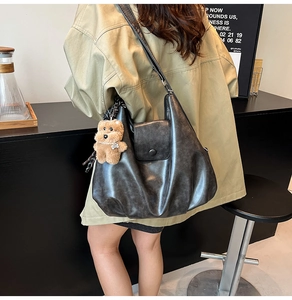 Detail of dark grey retro tote bag with washed texture and cute plush bear charm