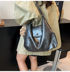 Detail view of large dark grey vintage hobo bag with teddy bear charm and wide strap