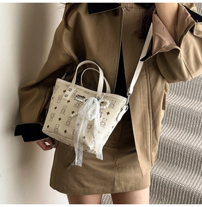 Détail du sac seau crème avec motif d'ours, nœud en dentelle et pendentif perle
