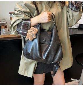 Detail of soft leather shoulder bag with vintage texture and cute bear pendant