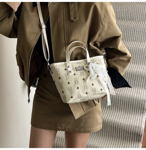 Détail du sac crème avec imprimé ours, ruban en dentelle et pendentif perle élégant